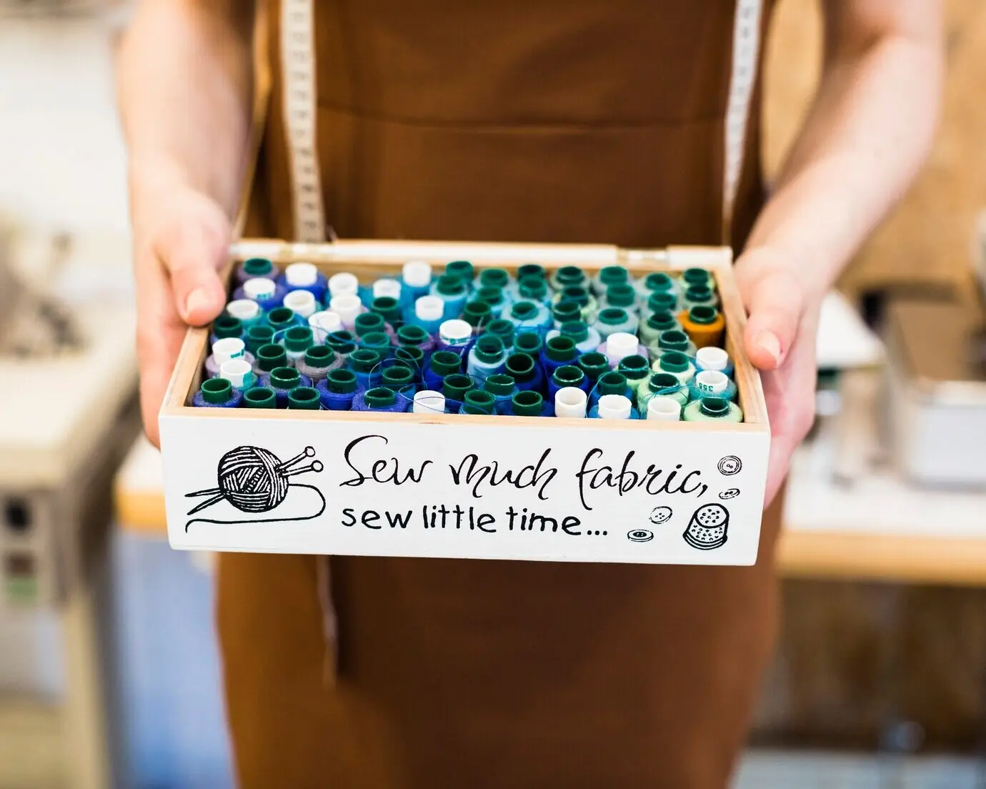 Nahaufnahme der Hand eines Modedesigners, die eine Fadenbox hält.