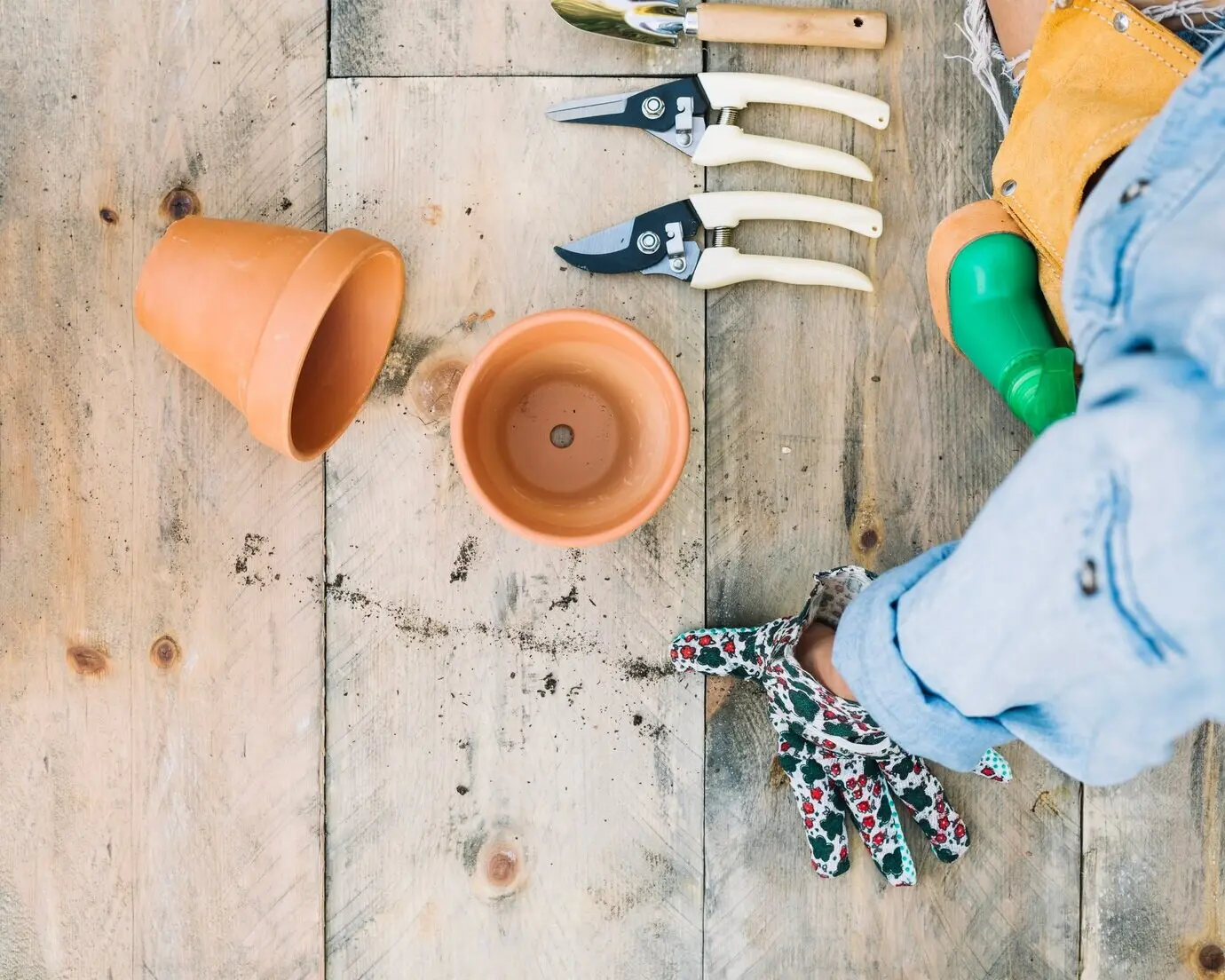 Zugeschnittene Aufnahme einer Frau neben Töpfen und Gartengeräten.